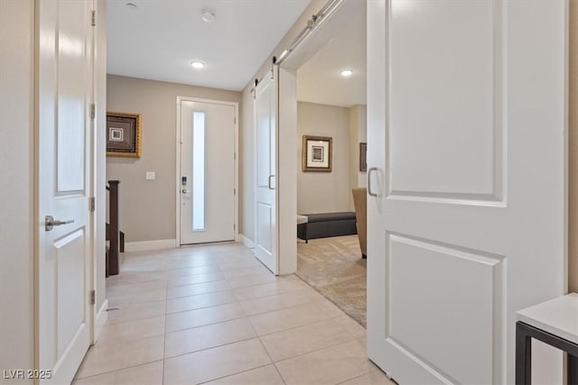 foyer entrance with light tile patterned floors, a barn door, recessed lighting, light carpet, and baseboards