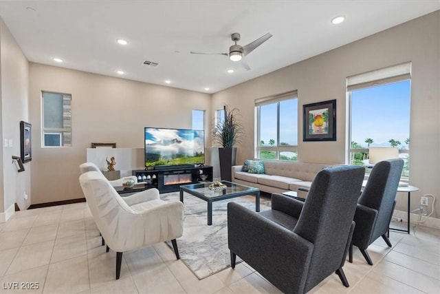 living room with recessed lighting, a glass covered fireplace, and baseboards