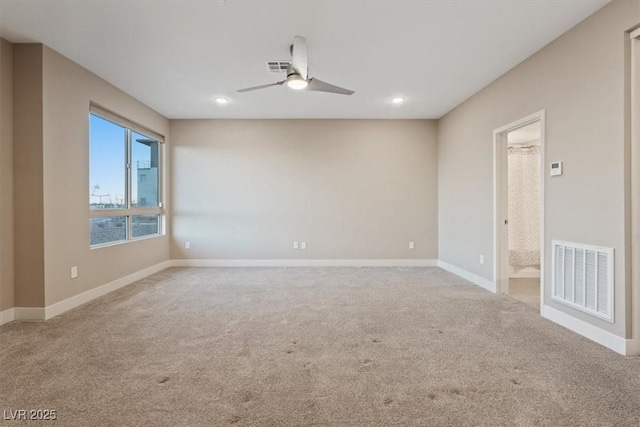 spare room with light colored carpet, visible vents, ceiling fan, and baseboards