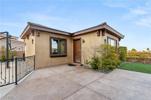 view of front facade featuring fence, a patio, and stucco siding