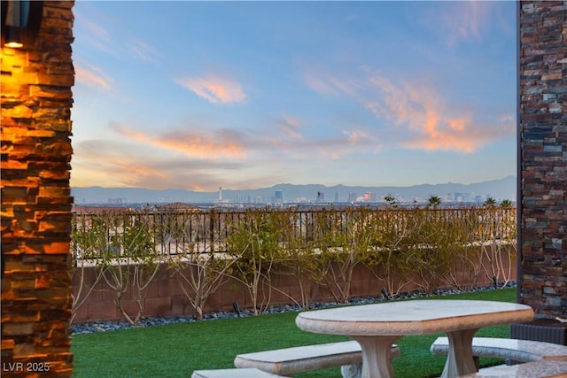 yard at dusk featuring a fenced backyard and a mountain view