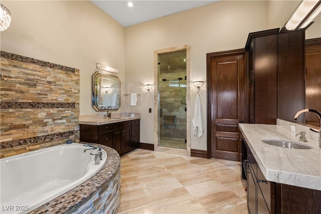 full bathroom featuring a garden tub, two vanities, a sink, baseboards, and a shower stall