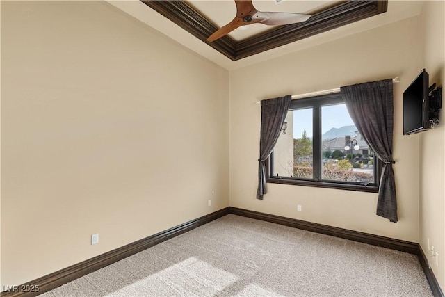 carpeted empty room featuring baseboards, a raised ceiling, a ceiling fan, and crown molding