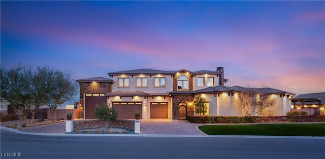 view of front of house featuring a garage, decorative driveway, and stucco siding