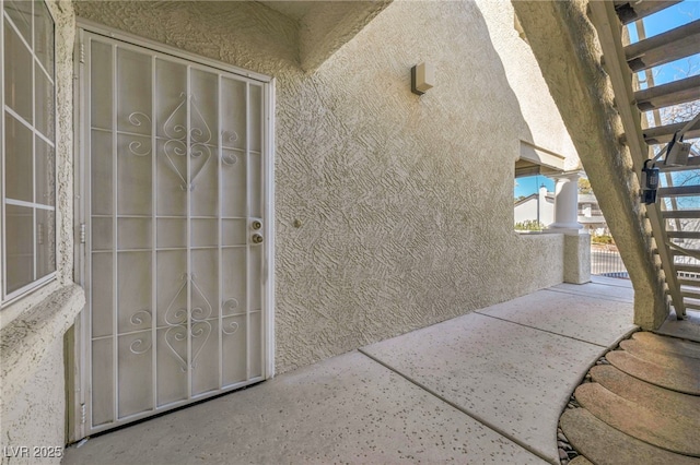 view of exterior entry featuring a gate and stucco siding