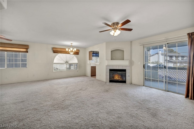 unfurnished living room featuring carpet, a tile fireplace, and ceiling fan with notable chandelier