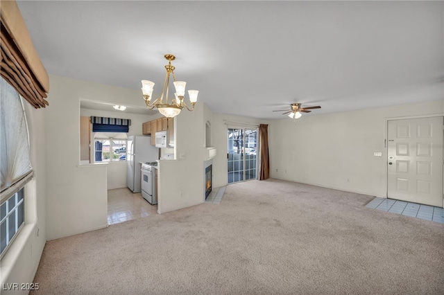 unfurnished living room featuring a fireplace with flush hearth, light colored carpet, and ceiling fan with notable chandelier