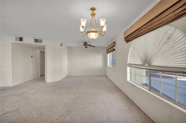 empty room featuring visible vents, light carpet, and ceiling fan with notable chandelier