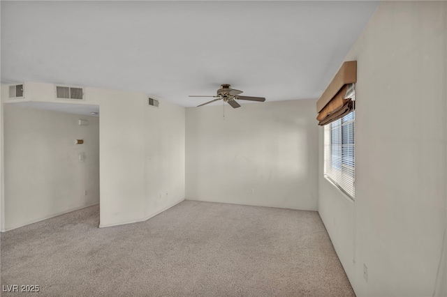 spare room featuring ceiling fan, visible vents, and light colored carpet