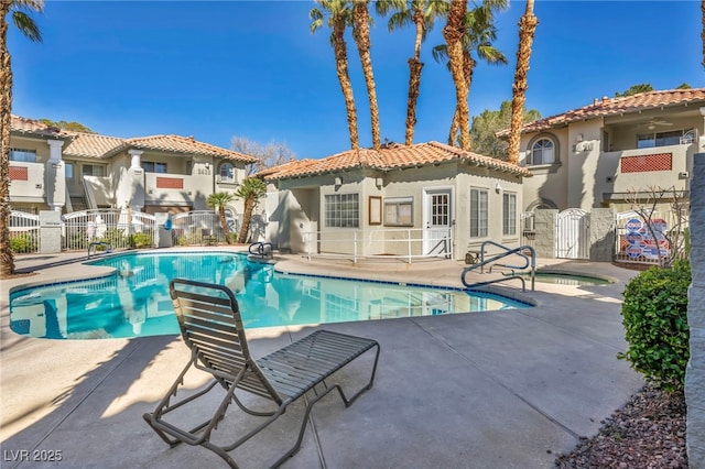 community pool with a gate, fence, and a patio