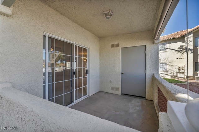 entrance to property with a balcony and stucco siding