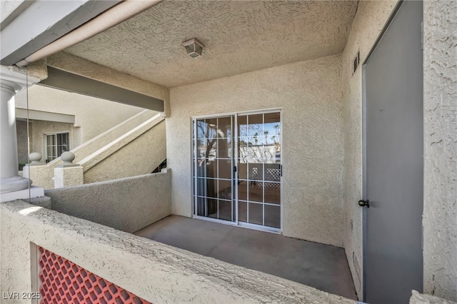 doorway to property with a balcony and stucco siding