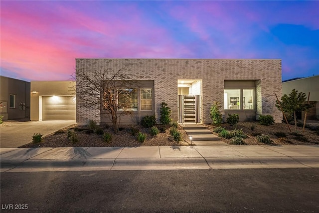 modern home featuring a garage, concrete driveway, and brick siding