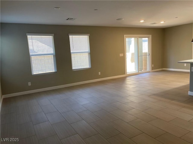 spare room featuring recessed lighting and baseboards