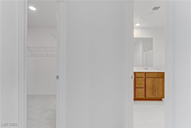 bathroom with a spacious closet, vanity, and recessed lighting