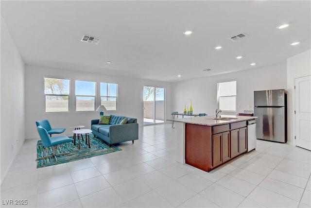 kitchen with appliances with stainless steel finishes, open floor plan, visible vents, and a sink