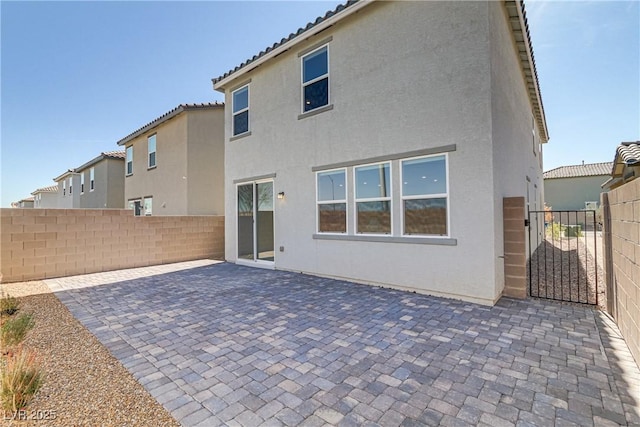 rear view of property featuring a patio, a tile roof, fence, and stucco siding