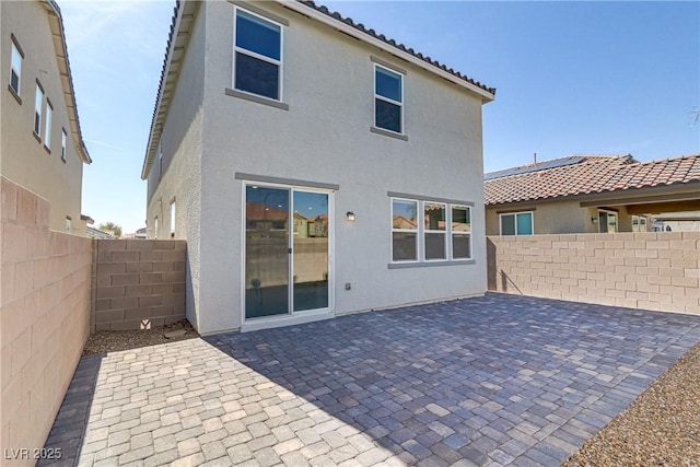 rear view of house featuring a patio, a tile roof, a fenced backyard, and stucco siding