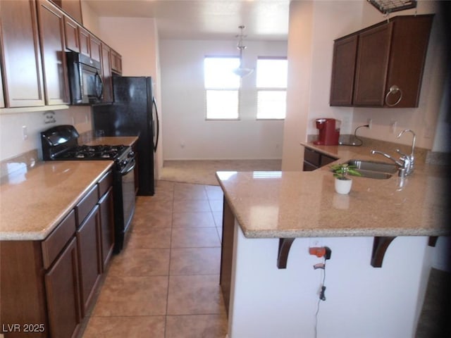 kitchen with a breakfast bar, hanging light fixtures, a sink, a peninsula, and black appliances