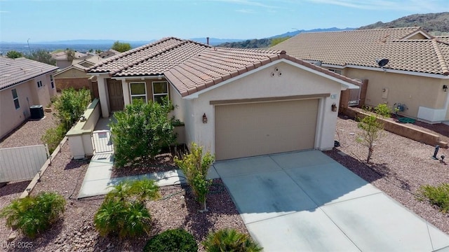 view of front of home with a garage, fence, concrete driveway, a tiled roof, and stucco siding