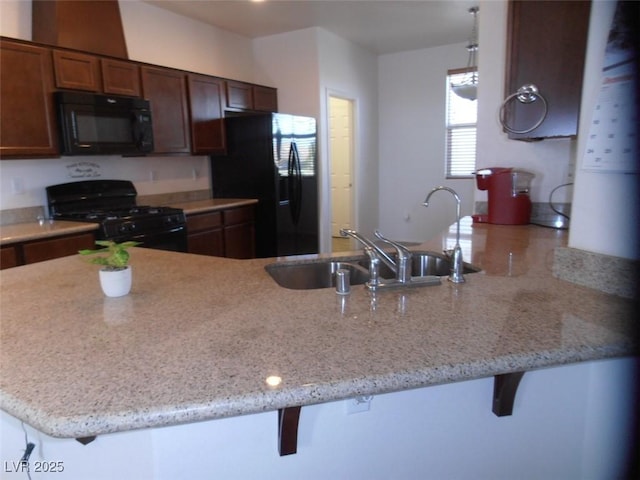 kitchen with black appliances, a breakfast bar, a peninsula, and a sink