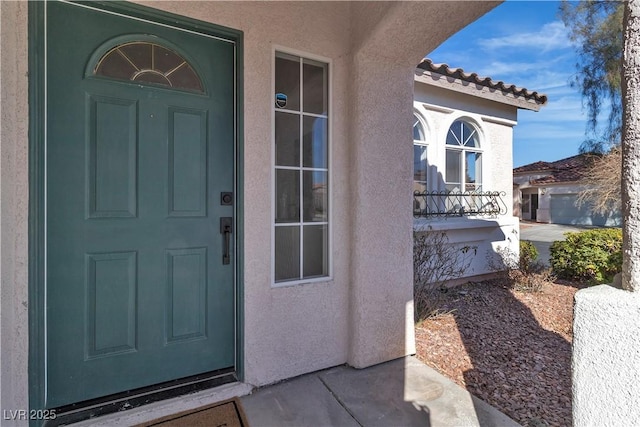 property entrance featuring a tile roof and stucco siding