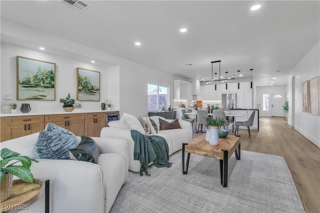 living area with wine cooler, light wood finished floors, recessed lighting, visible vents, and baseboards