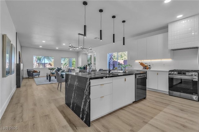 kitchen with a kitchen island, white cabinetry, open floor plan, stainless steel range with gas cooktop, and dishwasher