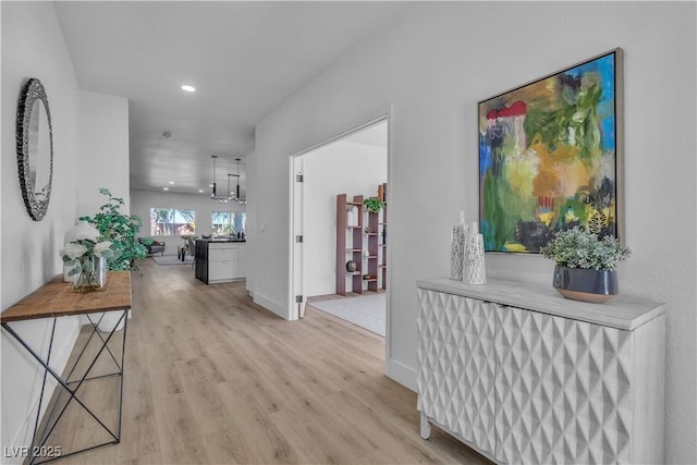 hallway featuring a chandelier, recessed lighting, light wood-style flooring, and baseboards