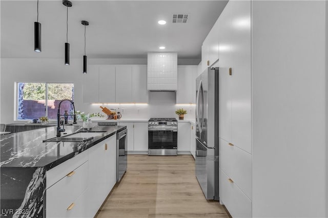 kitchen with decorative light fixtures, stainless steel appliances, white cabinets, a sink, and modern cabinets