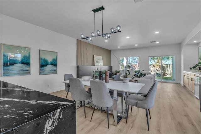 dining room with light wood-style floors, recessed lighting, baseboards, and an inviting chandelier