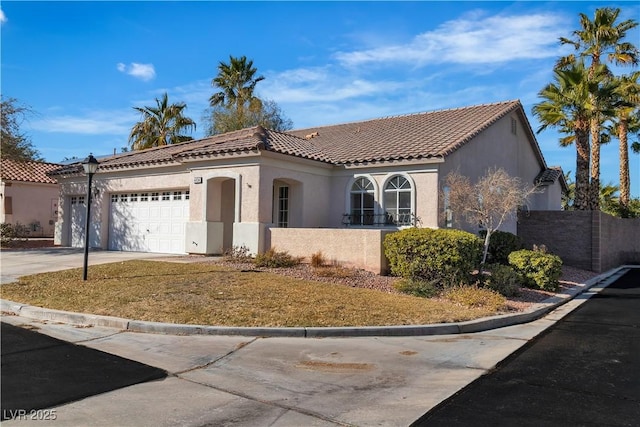 mediterranean / spanish home featuring an attached garage, driveway, a tile roof, and stucco siding