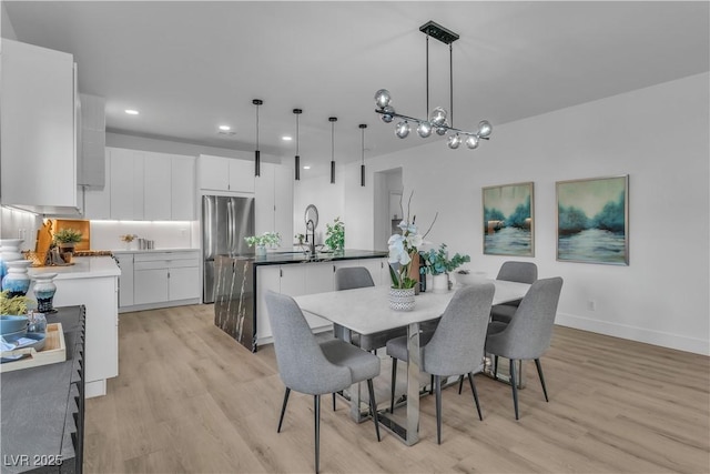 dining room featuring baseboards, light wood finished floors, an inviting chandelier, and recessed lighting