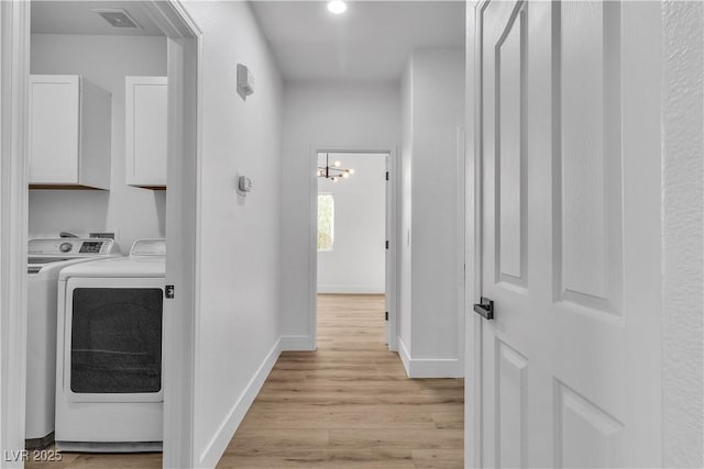 hallway with light wood-style floors, baseboards, visible vents, and separate washer and dryer