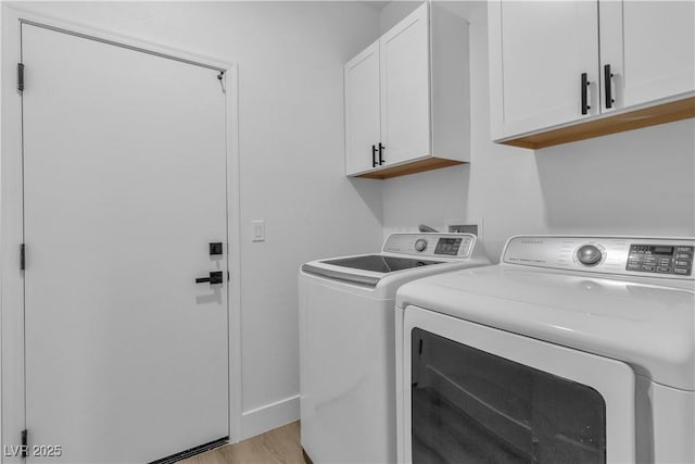 washroom with light wood-type flooring, baseboards, cabinet space, and washing machine and clothes dryer