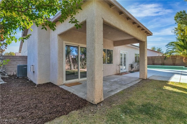 back of house with cooling unit, a fenced backyard, and stucco siding