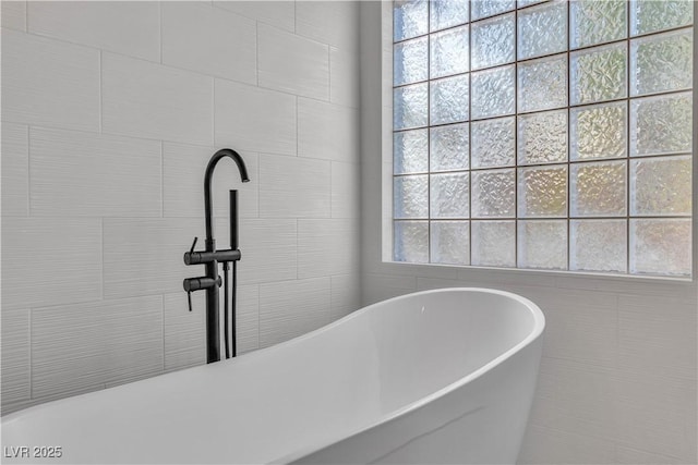 full bath with a freestanding tub and tile walls