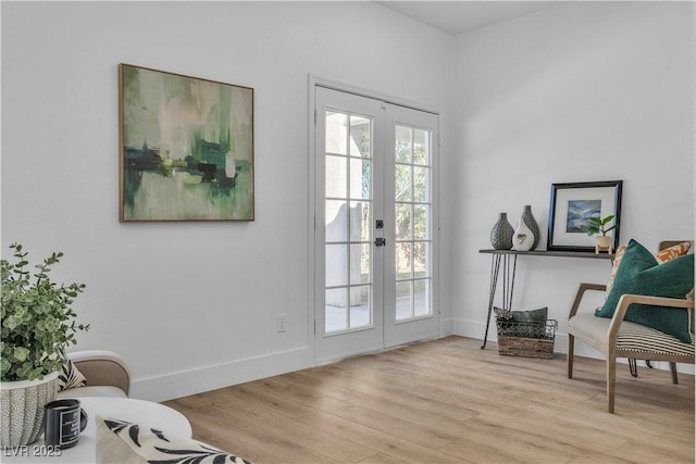 sitting room with french doors, light wood-type flooring, and baseboards