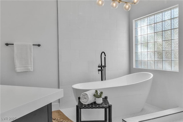 full bathroom with a soaking tub, tile walls, and vanity