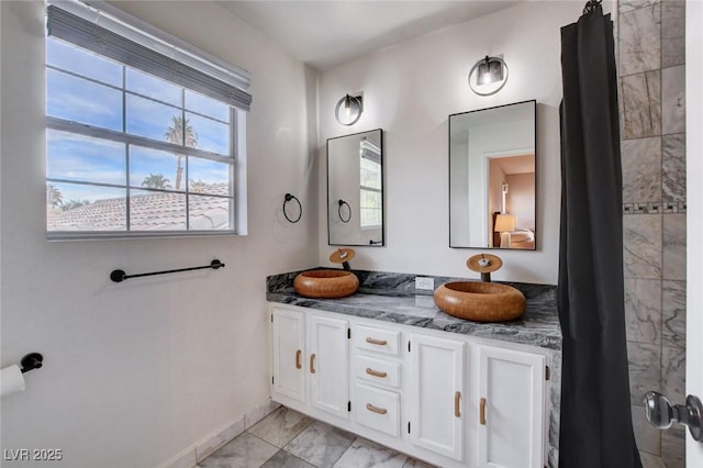 full bath with baseboards and double vanity