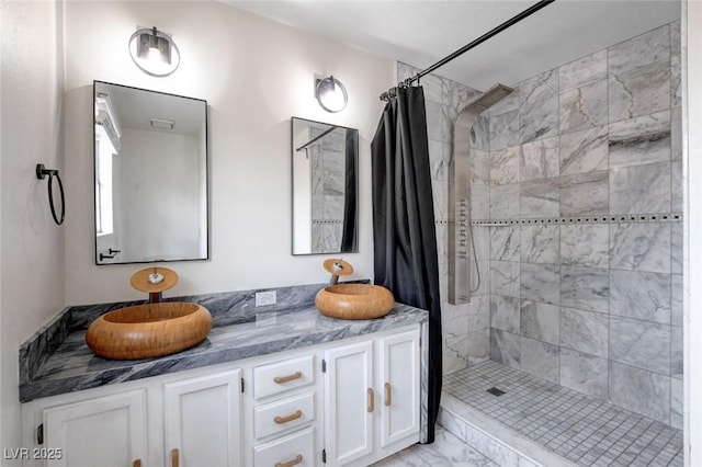 full bathroom with a stall shower, marble finish floor, and double vanity