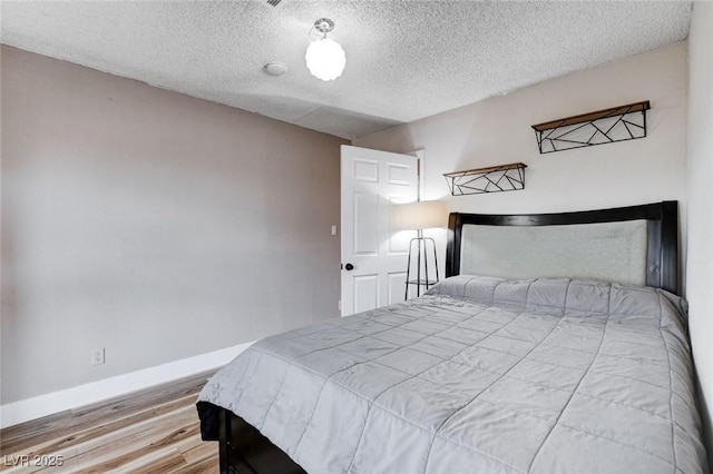 bedroom featuring a textured ceiling, wood finished floors, and baseboards