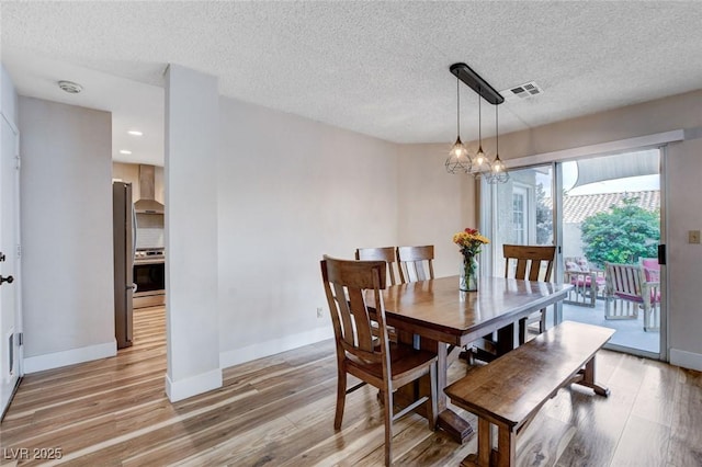 dining space with light wood finished floors, baseboards, visible vents, and an inviting chandelier