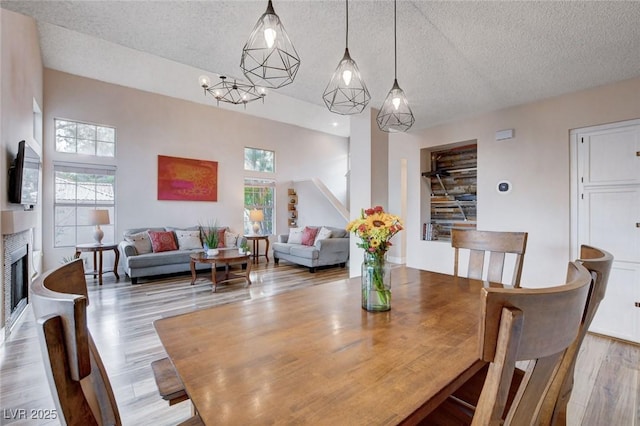 dining area featuring a textured ceiling, a fireplace, and light wood-style flooring