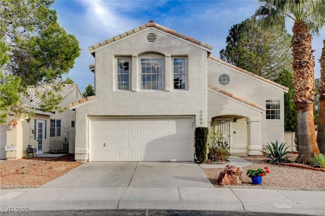 mediterranean / spanish-style home with a garage, a tiled roof, concrete driveway, and stucco siding