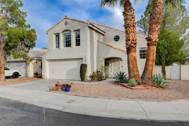 mediterranean / spanish home featuring driveway, an attached garage, a tiled roof, and stucco siding