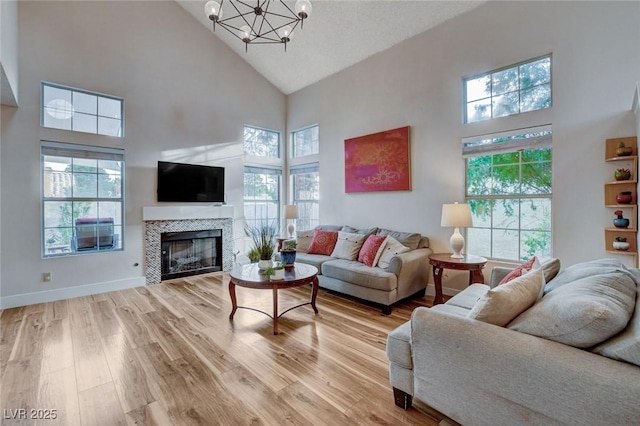 living room with a healthy amount of sunlight, light wood finished floors, baseboards, and a glass covered fireplace