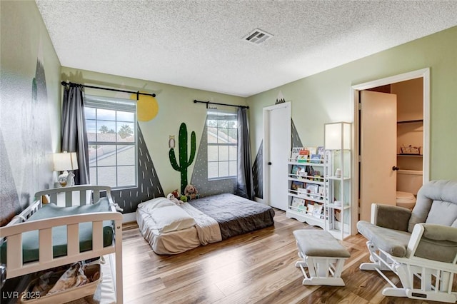 bedroom featuring a textured ceiling, visible vents, and light wood-style floors