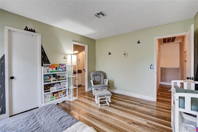 sitting room with baseboards, visible vents, and light wood finished floors