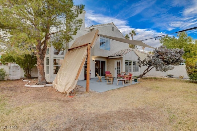 rear view of house featuring a yard, a patio, fence, and stucco siding